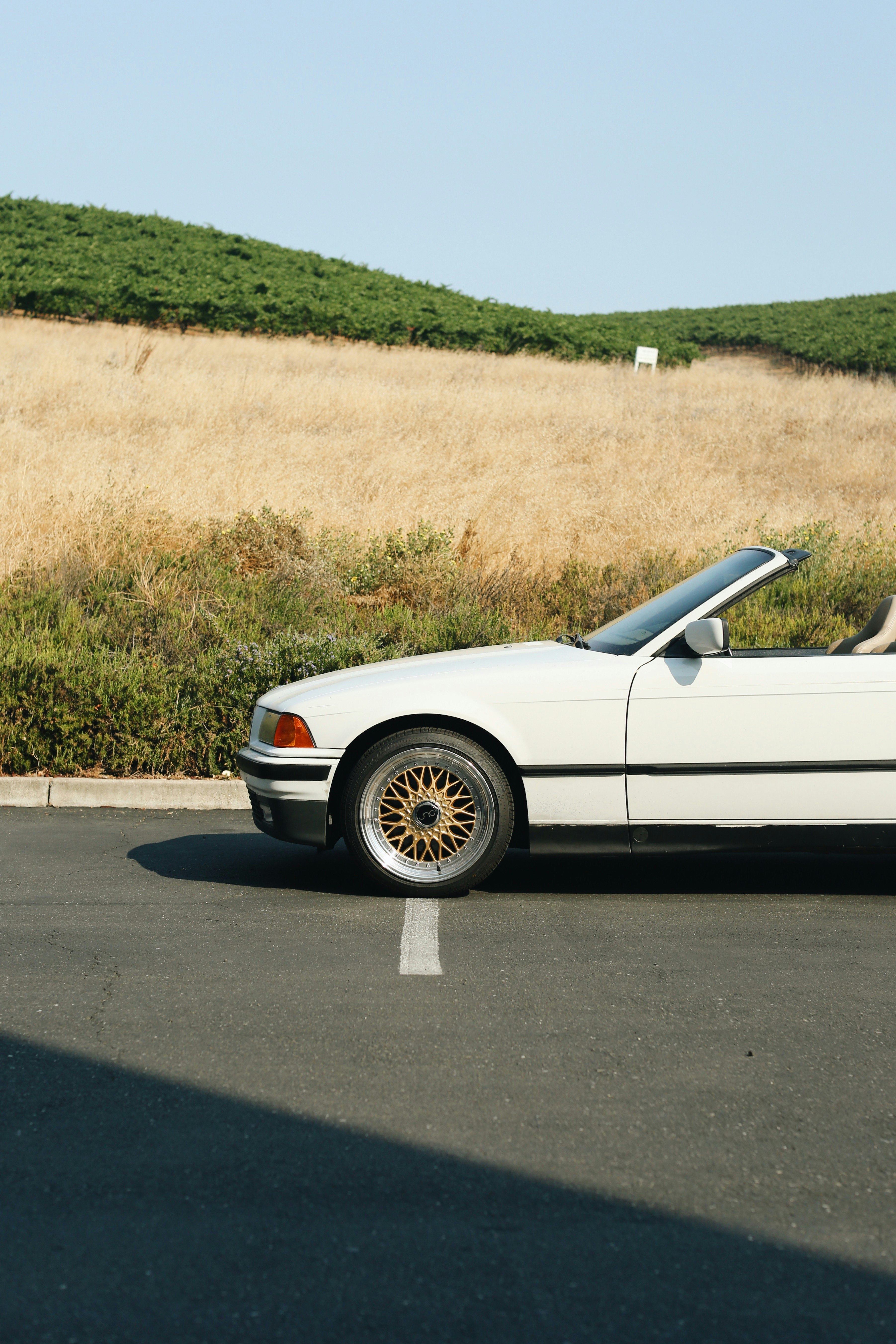 white coupe on gray asphalt road during daytime